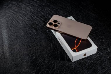 Jurmala, Letonya - 31.05.2025: Apple Iphone 16 Pro Desert Titanium. En son akıllı telefon modeli parlak bir çöl titanyum kaplamasında parlıyor. Orijinal ambalajının üzerine zarif bir şekilde yerleştirilmiş. Yüksek kalite