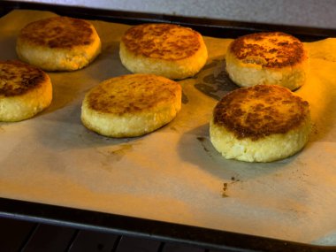 Altı yuvarlak altın kek sıcak bir mutfakta bir yemek tepsisinin üzerinde dinleniyor. İkramlar taze pişmiş ve kıtır kıtır, aile veya arkadaşlarla tatmayı ve paylaşmayı bekliyor..