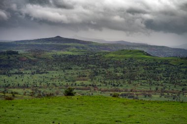 Yağmurlu sezon manzarası. Muson bulutları gökyüzünü kapladı ve tepeler yeşil çimlerle kaplandı bu da araziyi yeşile çevirdi..