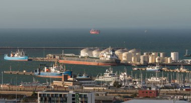 Cape Town, South Africa. 2023. Oil tanker offloading  cargo alongside oil storage tanks, port of Cape Town. clipart