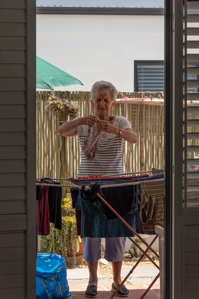 南非兰格班 2023年 白人老年妇女整理衣物 然后在庭院里烘干 — 图库照片