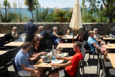 Herm, Channel Adaları, İngiltere. 11 Haziran 2023. Tatilciler dışarıda Herm Island restoranında yemek yiyorlar. Manzara Guernsey 'e doğru başka bir Kanal Adası' na doğru..