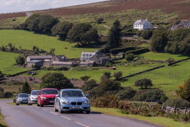 Dartmoor Ulusal Parkı, Devon, İngiltere, İngiltere. 4 Eylül 2023. Dartmoor 'da, Merrivale köyü, Devon, İngiltere' nin arka planında, ulusal park boyunca giden motorlu araçlar.