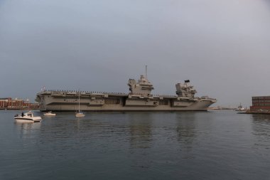Portsmouth, İngiltere, İngiltere. 8 Eylül 2023. HMS Kraliçesi Elizabeth hava kararınca Portsmouth tersanesinden römorkör ve güvenlik gemileriyle ayrılıyor. Donanma personeli güverteleri doldursun.. 