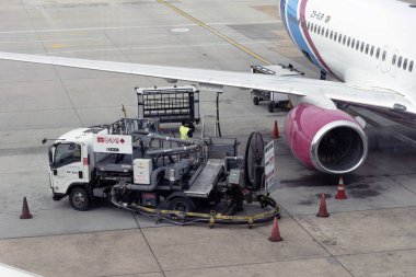 Cape Town, South Africa. 30 April 2024.  Fuel supply truck filling  a passenger jet aircraft on the airport apron via a pipe attached beneath the wing. clipart