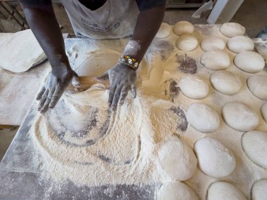 Yzerfontein Batı Cape Güney Afrika 'da. 19.04.2024. Bir fırında hamur toplarından pizza yapmak için hamur işleriyle uğraşan bir fırıncının bakış açısı..