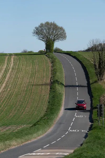 Hampshire İngiltere. 04.04.2025. İngiltere 'de Hampshire' da İngiliz köy yolunda kırmızı bir araba..