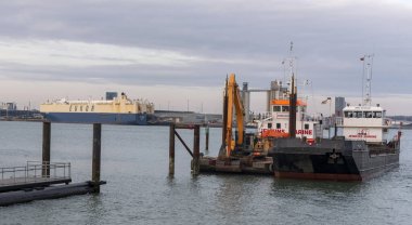 İngiltere 'nin Southampton Su İşleri. 09.03. 2025 yılı. Dalgıç teknesi ve mavna Southampton 'da çalışıyor. Hythe' ye yakın bir yerde, bu su yolunun batı kıyısında..