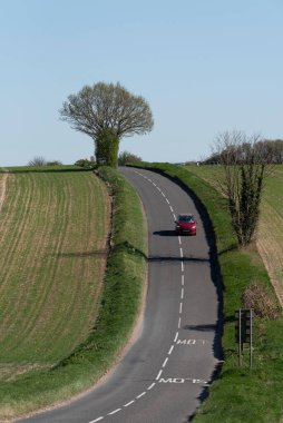 Hampshire İngiltere. Mayıs 2025. Winchester yakınlarındaki kırsal bir yolda kırmızı araba Hampshire İngiltere 'de.