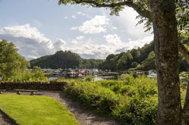 Balmaha Gölü Balmaha, Lomond İskoçya UK.06.07.2025. Balmaha 'daki Lomond Gölü' nün kıyısındaki küçük tekneler buradan Batı Highlands Yolu gölün kıyısında devam ediyor.., 