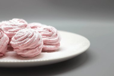 Gri arka planda beyaz bir tabakta el yapımı şekerlemeler..