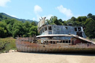 Old wooden wrecked ship on the shore. Light photo on a sunny day clipart