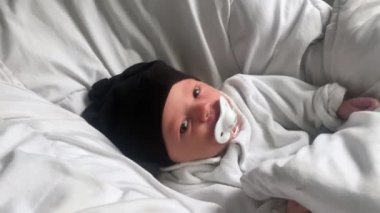 Yeni doğmuş güzel bir kız bebek bir beşikte yatıyor ve yakından gülümsüyor.