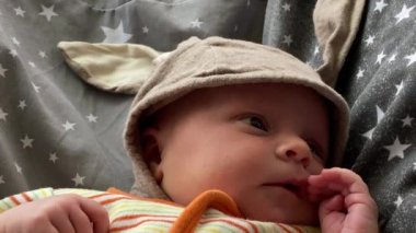 Küçük güzel bebek kanepeye yakın plan beyaz elbiseli ve bereli.