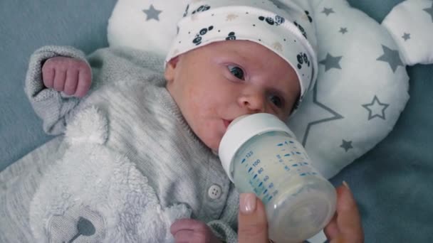 母親は娘の子供にミルクの哺乳瓶を家で与えている 肖像赤ちゃんの食事 粉ミルクを飲む — ストック動画