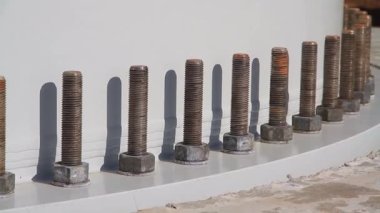 Rüzgar türbini temeli. Üste sürgüler var. Rüzgar türbini kulesi yapısını yerinde tutuyor. Rüzgâr çiftliği inşaatı. Cıvatalar yakın planda bağlanıyor