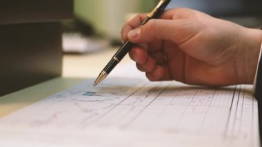 İstatistik çizelgesi ve yatırım projesi yakın plan çizelgesi yönetici masasında. El kalemi belgenin üzerine taşır