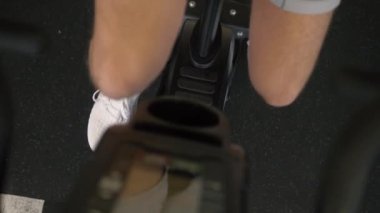 Spor salonunda egzersiz bisikleti kardiyo dayanıklılık eğitimi alan bir erkek sporcu.