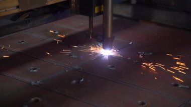 Industrial laser machine cuts parts from thick sheet steel metal. Close-up with sparks machine cuts sheet of steel into different shapes