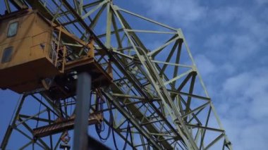 Yellow industrial gantry crane at the construction site. The control cabin in motion on the production of heavy industry