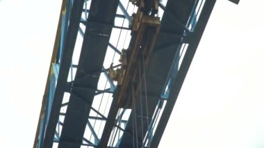 Mavi gökyüzüne karşı Gantry vinci kayar vinçler ve halatlar kargo taşır. Metal ürünleri fabrikasında vinç kullanarak inşaat