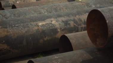Metal borular açık havada bir depoda yatıyor. Fabrikadaki rulo metalin ürünü. Yuvarlanan metal üretiminin bitmiş ürünlerinin deposu.
