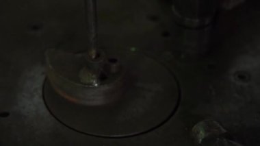 Demirci, metal çubuğu otomatik örse takar. Kapıda süs eşyası, yakın plan metal işlemeli.