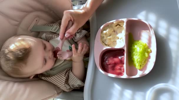 朝一番の食事は台所のスプーンから赤ん坊を食べる母親 — ストック動画