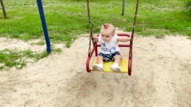 Küçük güzel ve mutlu kız yazın salıncakta sallanıyor.