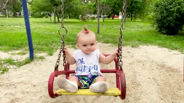 Babyspaziergänge Und Schaukeln Auf Der Spielplatzschaukel Bei Klarem Sommerwetter — Stockvideo