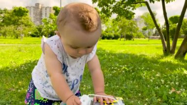 Küçük bir kız çocuğu çimlerin üzerinde parkta oyun oynuyor.