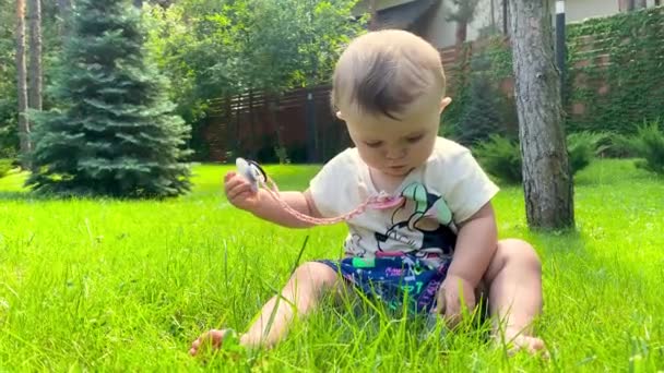 赤ん坊は緑の芝生の外で芝生で遊んでいる 自然の中で可愛い女の子 — ストック動画
