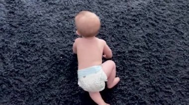 Bebek yerde sürünerek ailesine doğru gidiyor. Mutlu bebek yürümeyi öğrenmeye başlar.