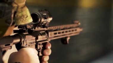 Kamuflaj üniformalı bir adam atış poligonunda makineli tüfekle ateş ediyor.