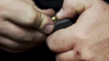 Erkeklerin elleri bir makineli tüfeğin şarjörüne cephane yüklüyor.