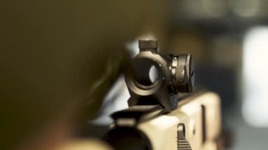 man in a camouflage uniform looks through the telescopic sight of a machine gun at a shooting range at a shooting range
