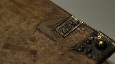 Bir arşivde çekilen bu nadir kitap deri ve metal klipsleri çatlattı. Yüzeyde ağır çekim tavası. Restorasyon ve araştırma temaları için harika