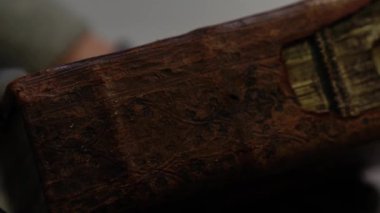 Kırık deri, açıkta kalmış iplikler ve hasarlı kapağı olan eski bir kitabın yakın çekimi. Tarih, arşiv, restorasyon ve antika korunumu konuları için mükemmel.