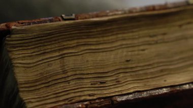 Kırık deri ve metal elementlerle dolu eski bir arşiv kitabı. Kamera yavaşça yüzeyinde kayar. Tarih, arşiv ve antika korunumu temaları için ideal