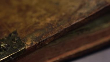 Eski kitap kapağında çatlak deri ve süslü metal parçalar yer alıyor. Kamera yavaş yavaş oradan geçiyor. Tarih, miras veya kütüphane konuları için idealdir.