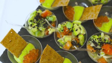 Kırmızı havyar, avokado, deniz ürünleri ve cam porsiyon kaselerde çıtır çıtır cipsli mini aperatifler. İyi yemek ve moleküler gastronomi sunumu