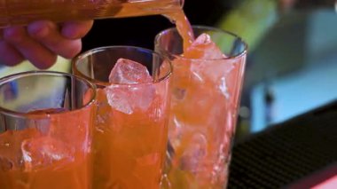 Yaz portakalı kokteyli yapmak: barmen buzlu uzun bardaklara soda ekler. Akşam barı havası ve ferahlatıcı içecek tadı.