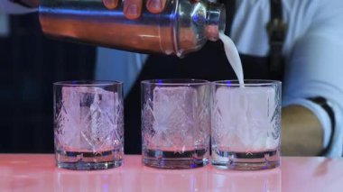 Önlüklü barmen, metal karıştırıcıdan bar tezgahına beyaz kokteyl döker. Barda imzalı bir içki hazırlama süreci