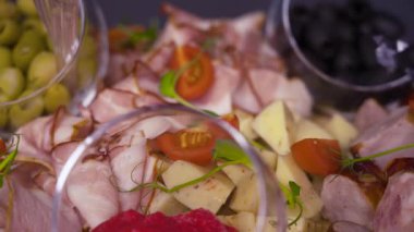 Dilimlenmiş et, peynirli küp, zeytin, siyah zeytin ve vişneli domatesli lezzetli mezeler. Şölen, yemek servisi ya da şenlik masası için şık bir yemek sunumu.