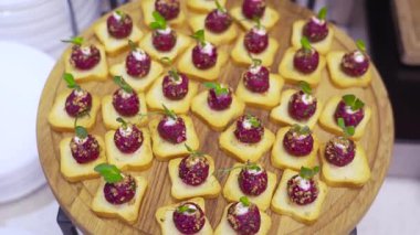 Pancar kökü kremalı, otlu ve yuvarlak ahşap tepside kraker bulunan zarif kanepelerin üst görüntüsü. Yemek, etkinlik ve gurme mutfak kavramları için mükemmel.