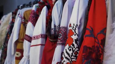 Orijinal Ukraynalı işlemeli gömlekler ve askıda asılı geleneksel halk kostümleri. Kırmızı ve siyah nakış desenli ulusal kıyafetler.
