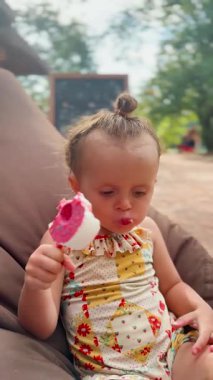 Gülümseyen küçük kız dışarıda dondurma yiyor. Yemek reklamı, aile hayatı ve yaz eğlencesi için mükemmel.