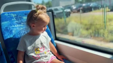 Küçük kız yolculuk sırasında tuhaf bir şekilde tren penceresinden dışarı bakıyor. Çocukluğun, seyahatin ve keşfin sembolü