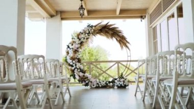Pastel çiçeklerle süslenmiş Boho düğün kemeri, otlar, beyaz sandalyeler, hareket eden kameralar. Yüksek kaliteli FullHD görüntüler