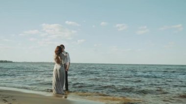 Sahilde birlikte koşan mutlu çift harika ve çok romantik hissediyorlar, el ele tutuşuyorlar ve ayakları suyun üzerinde yürüyorlar. Yüksek kalite 4k görüntü